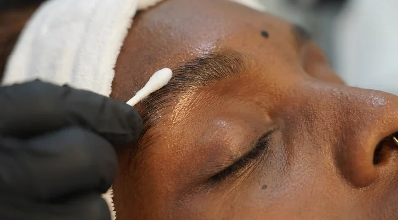 Nahaufnahme: Die Fixierlotion wird mit dem Wattestäbchen auf die Braue aufgetragen