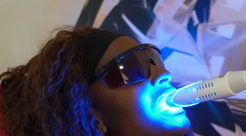 A client's teeth are cosmetically brightened using blue light in the Lucerne salon