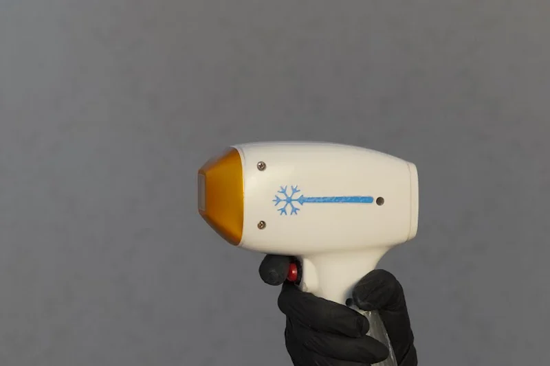 Das Laser-Handstück im Studio: weisses Gehäuse mit Schneeflocken-Symbol und goldener Frontplatte