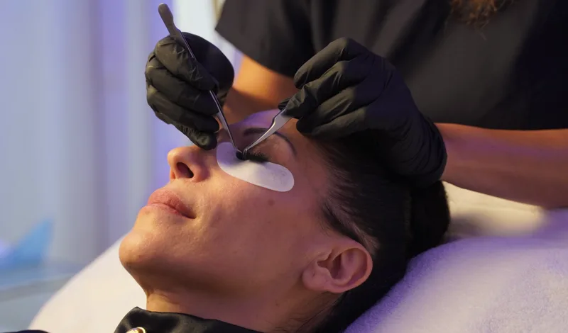 Wimpernverlängerung mit zwei Pinzetten: eine Naturwimper wird isoliert und die Extension angesetzt