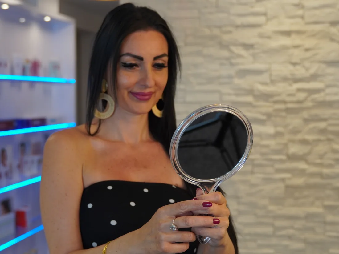 Kundin im Beauty Rocío Luzern betrachtet ihr fertiges Make-up im Handspiegel